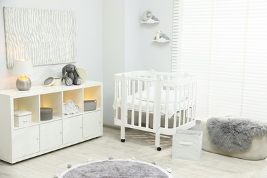 Photo of Beautiful baby room interior with stylish crib, other furniture and toys
