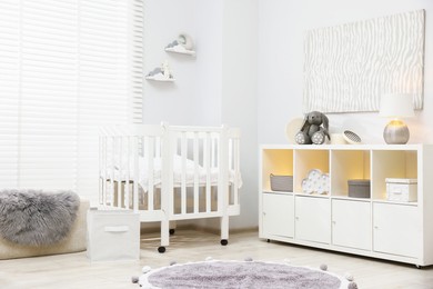Photo of Beautiful baby room interior with stylish crib, other furniture and toys