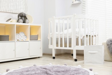 Photo of Beautiful baby room interior with stylish crib, other furniture and toys