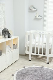Photo of Beautiful baby room interior with stylish crib, other furniture and toys