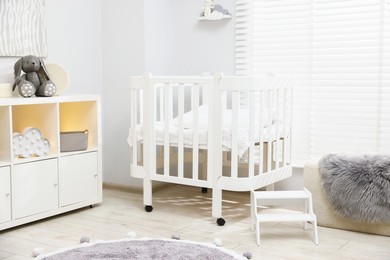 Photo of Beautiful baby room interior with stylish crib, other furniture and toys