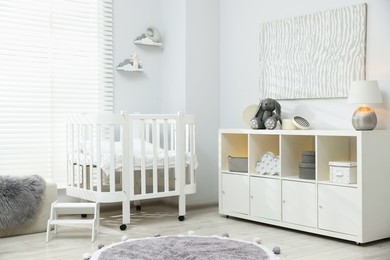 Photo of Beautiful baby room interior with stylish crib, other furniture and toys