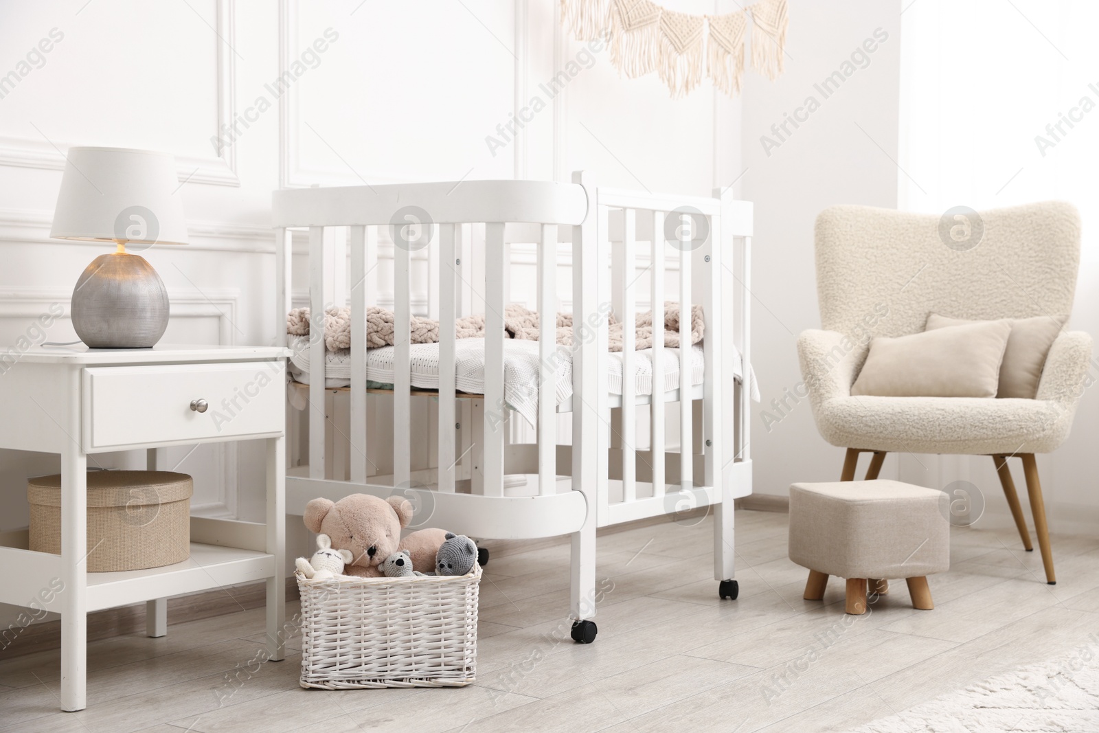 Photo of Stylish baby room interior with comfortable crib, armchair and toys
