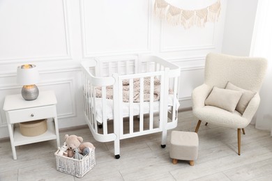 Photo of Stylish baby room interior with comfortable crib, armchair and toys