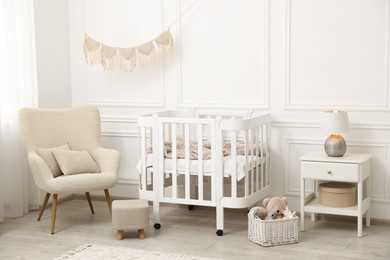 Photo of Stylish baby room interior with comfortable crib, armchair and toys