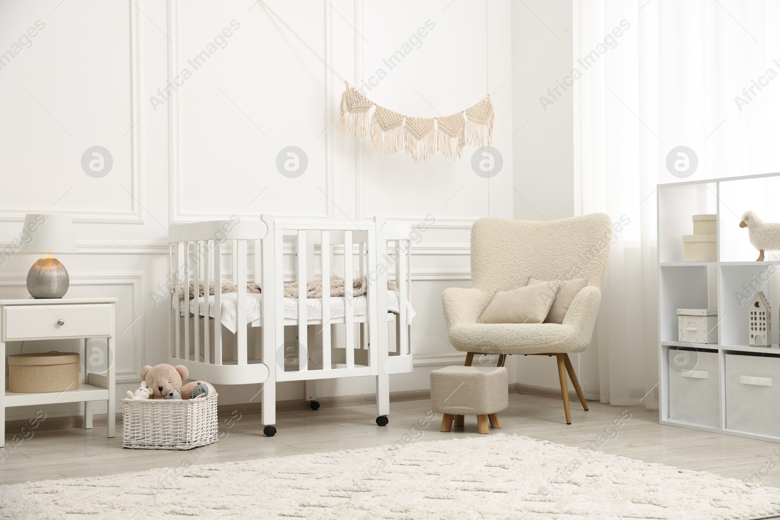 Photo of Stylish baby room interior with comfortable crib, armchair and toys