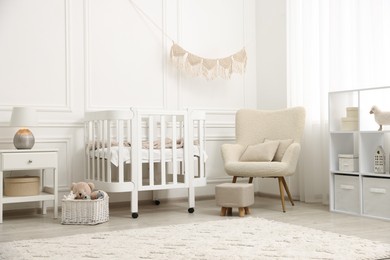 Photo of Stylish baby room interior with comfortable crib, armchair and toys