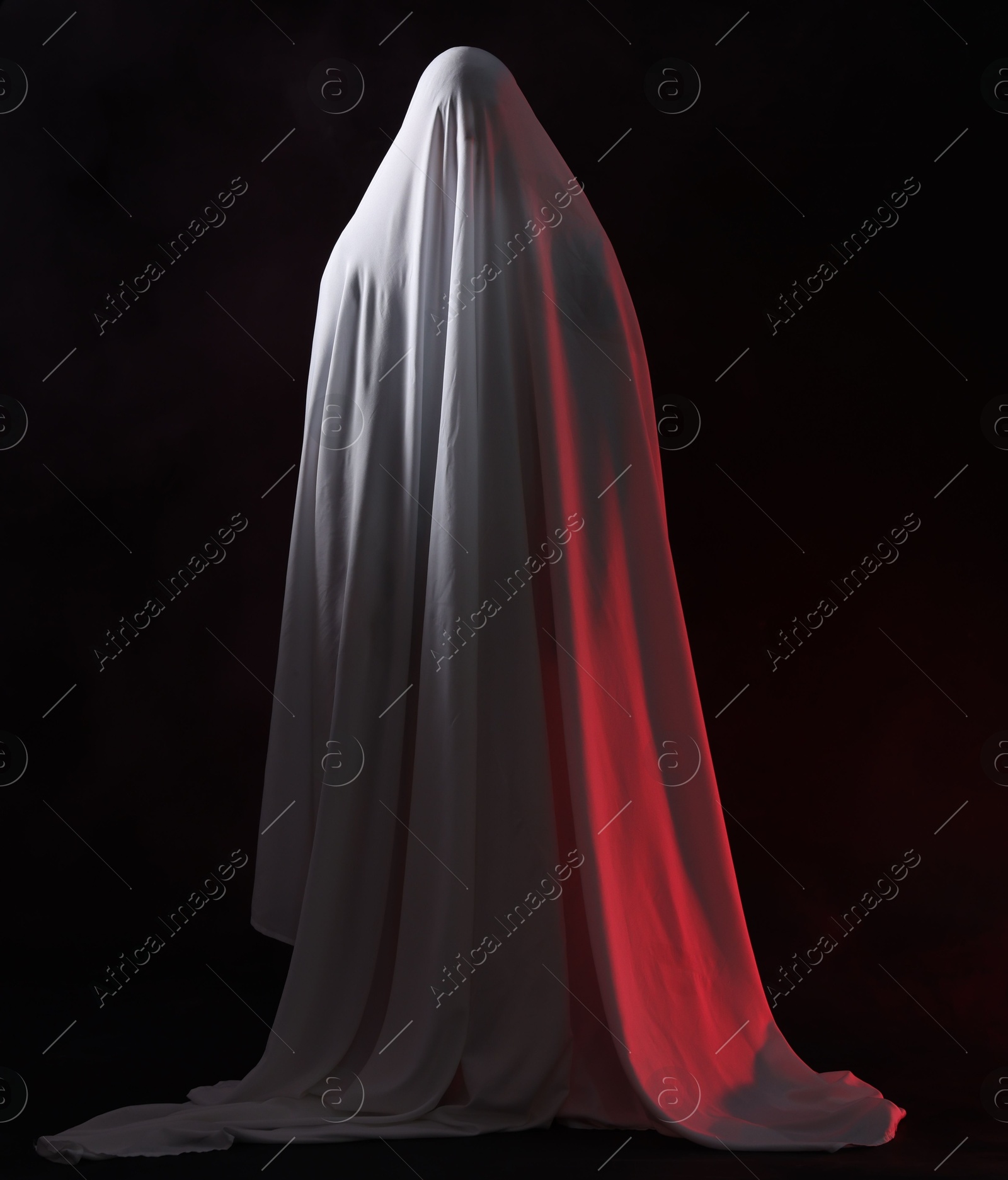 Creepy ghost. Man covered with white sheet on black background Photo of Creepy ghost. Man covered with white sheet on black background