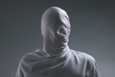 Photo of Creepy ghost. Man covered with white sheet on light grey background