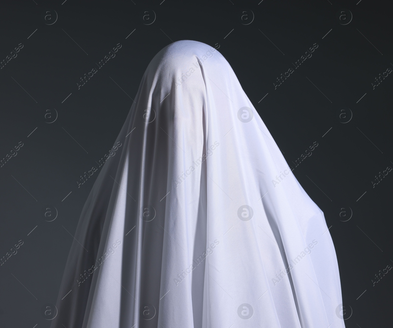 Creepy ghost. Man covered with white sheet on light grey background Photo of Creepy ghost. Man covered with white sheet on light grey background