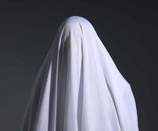 Photo of Creepy ghost. Man covered with white sheet on light grey background