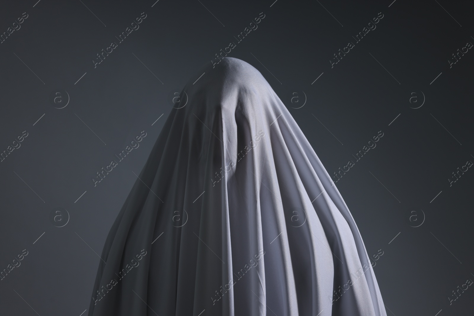 Creepy ghost. Man covered with white sheet on light grey background Photo of Creepy ghost. Man covered with white sheet on light grey background