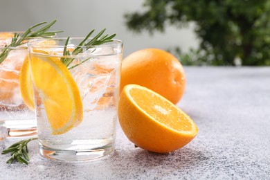Photo of Sparkling water with orange slices and rosemary on grey table, closeup