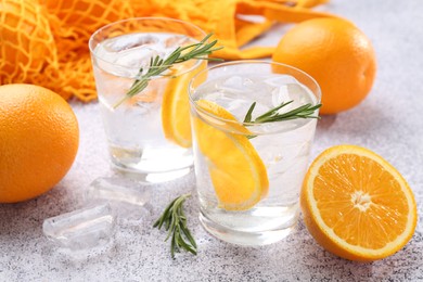 Photo of Sparkling water with orange slices and rosemary on grey table, closeup