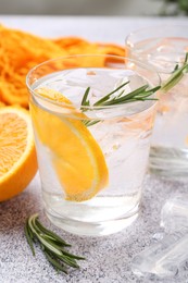 Photo of Sparkling water with orange slices and rosemary on grey table, closeup