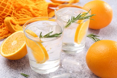 Photo of Sparkling water with orange slices and rosemary on grey table, closeup