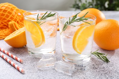 Photo of Sparkling water with orange slices and rosemary on grey table, closeup