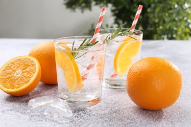 Photo of Sparkling water with orange slices and rosemary on grey table, closeup