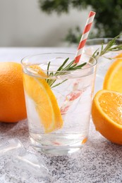Photo of Refreshing soda water with orange slices and rosemary on grey table, closeup