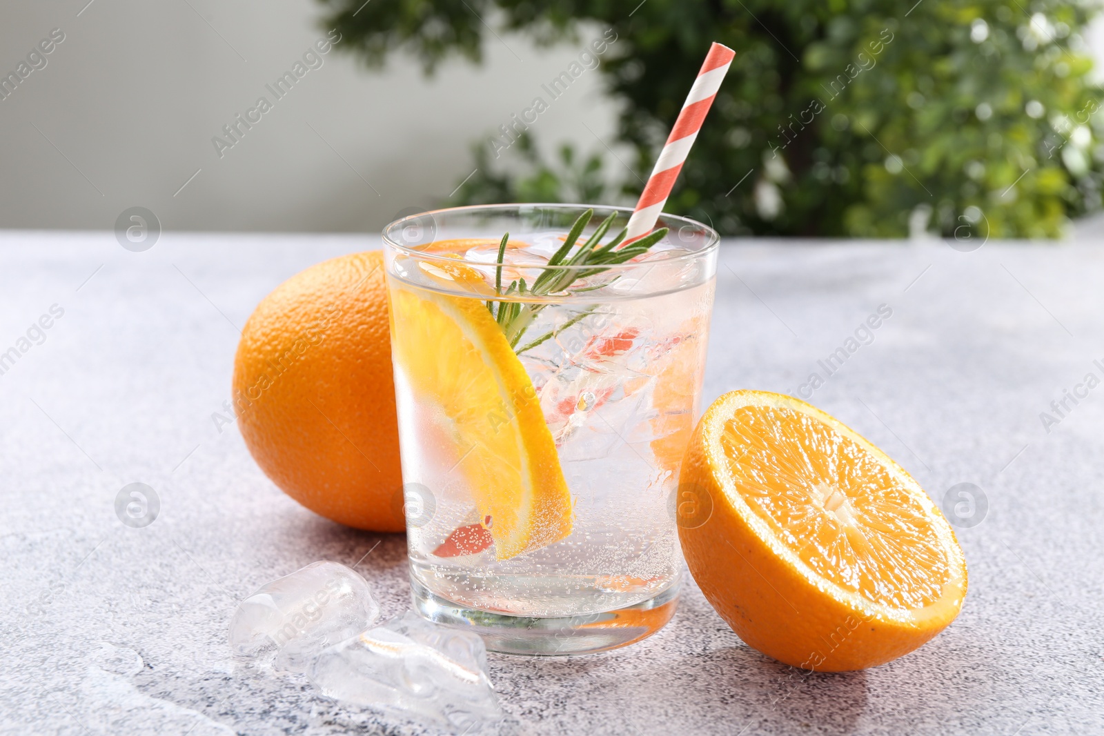 Photo of Refreshing soda water with orange slices and rosemary on grey table, closeup