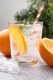 Photo of Refreshing soda water with orange slices and rosemary on grey table, closeup