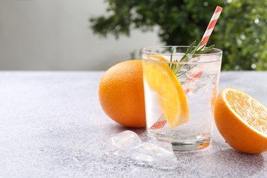 Photo of Refreshing soda water with orange slices and rosemary on grey table, closeup. Space for text