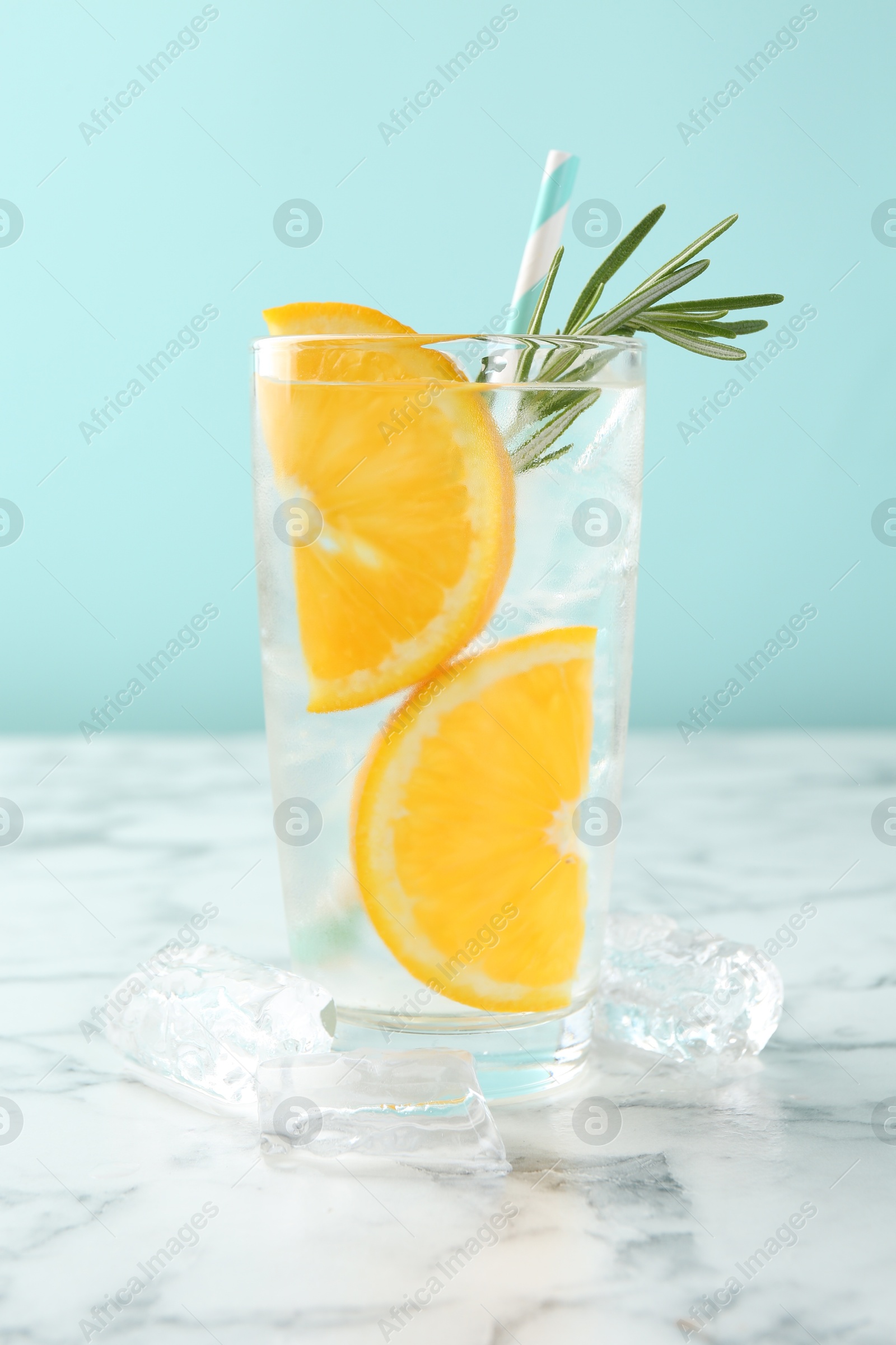 Photo of Refreshing soda water with orange slices and rosemary on white marble table, closeup
