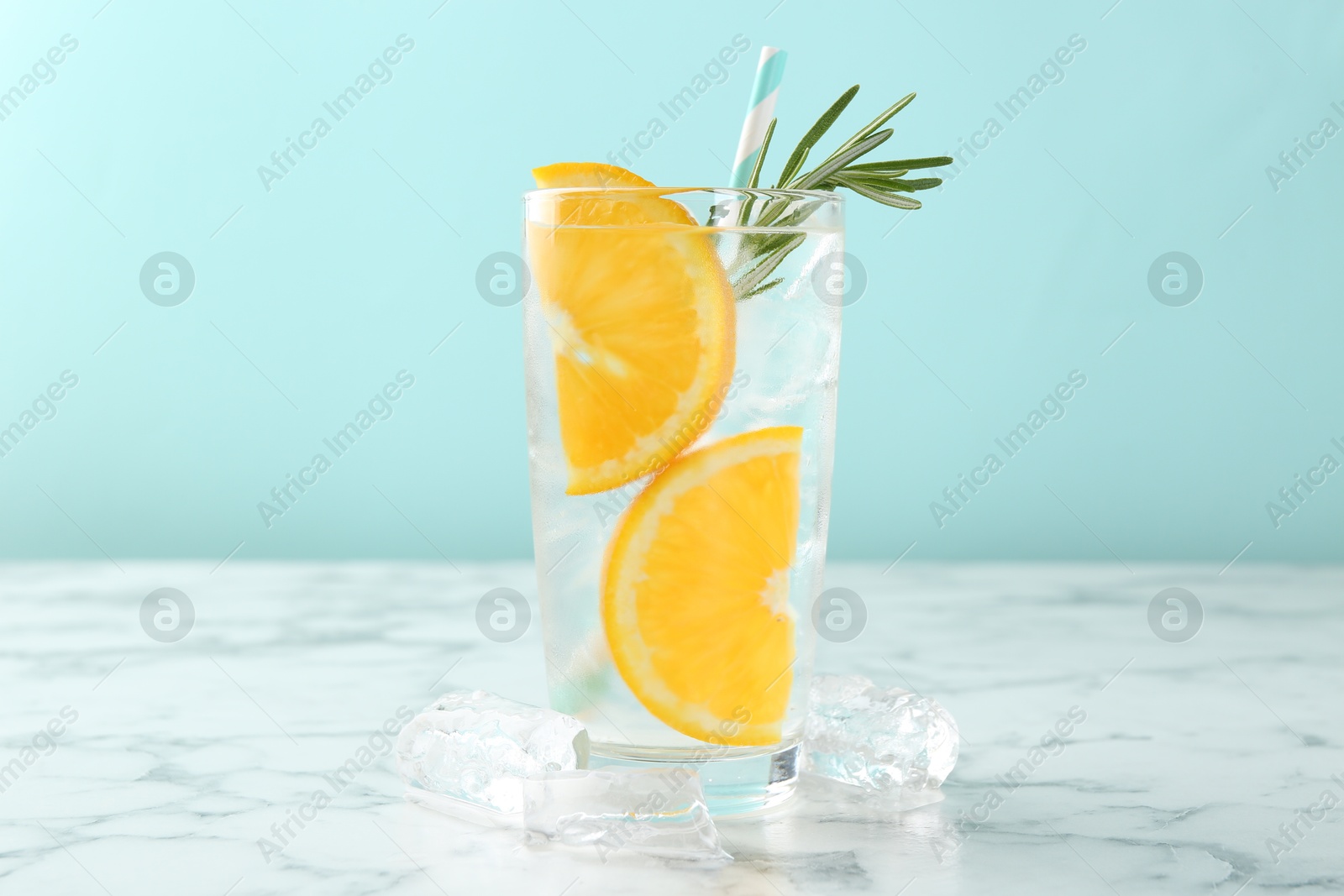 Photo of Refreshing soda water with orange slices and rosemary on white marble table, closeup