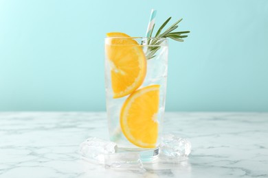 Photo of Refreshing soda water with orange slices and rosemary on white marble table, closeup