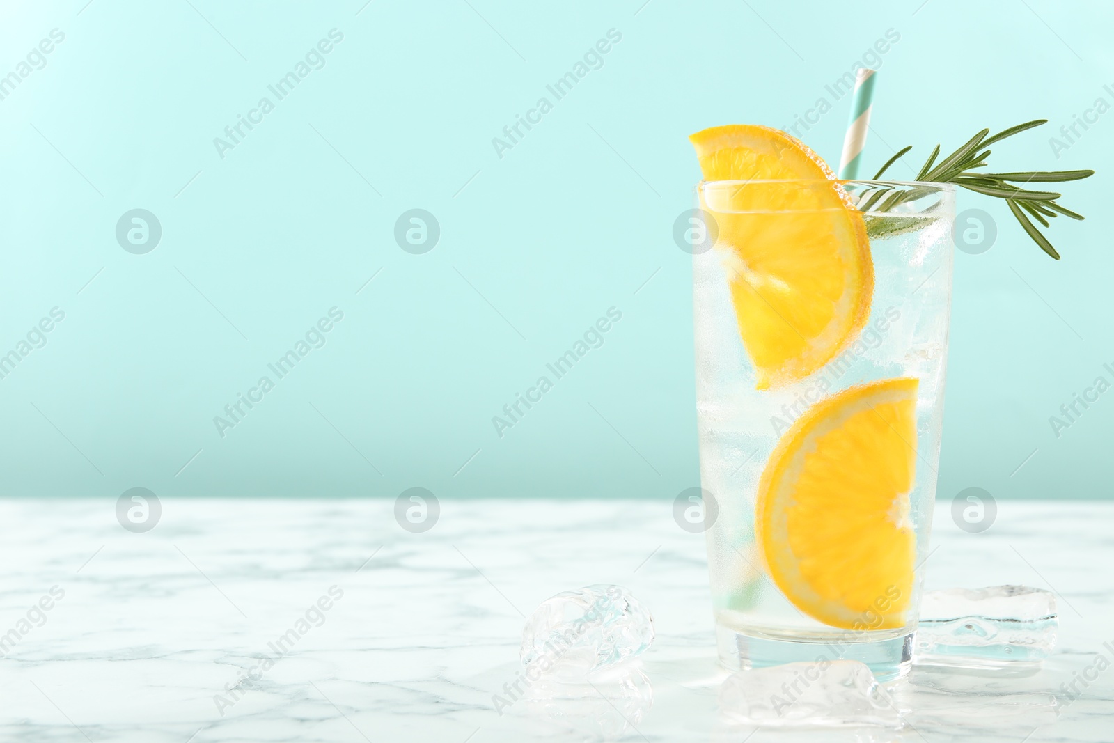 Photo of Refreshing soda water with orange slices and rosemary on white marble table, closeup. Space for text