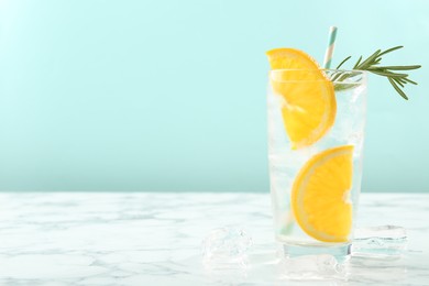 Photo of Refreshing soda water with orange slices and rosemary on white marble table, closeup. Space for text