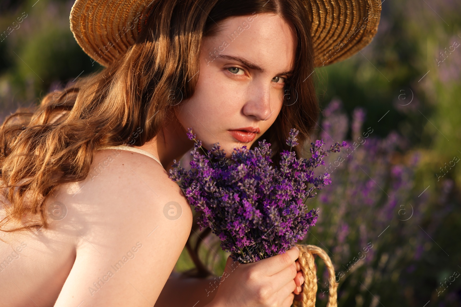 Beautiful young woman with lavender flowers in field, closeup Photo of Beautiful young woman with lavender flowers in field, closeup