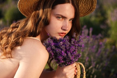 Photo of Beautiful young woman with lavender flowers in field, closeup