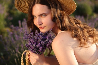 Photo of Beautiful young woman with lavender flowers in field, closeup