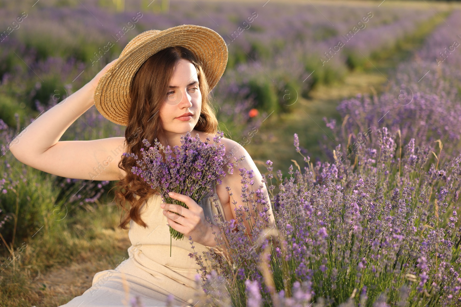 Beautiful young woman with lavender flowers in field Photo of Beautiful young woman with lavender flowers in field