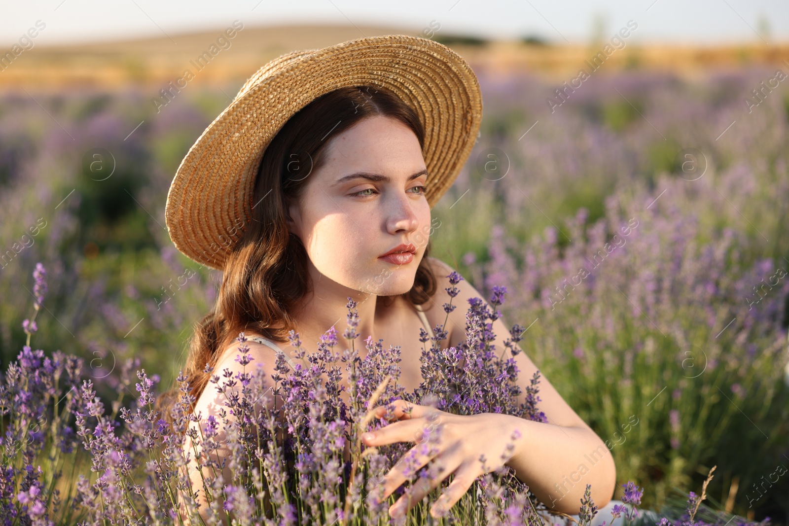 Beautiful young woman among lavender flowers in field Photo of Beautiful young woman among lavender flowers in field