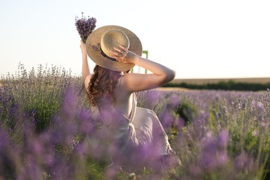 Photo of Woman with beautiful lavender flowers in field, back view