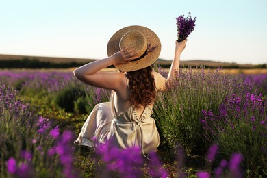 Photo of Woman with beautiful lavender flowers in field, back view