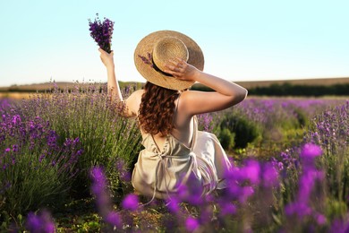 Photo of Woman with beautiful lavender flowers in field, back view