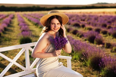 Photo of Beautiful young woman with lavender flowers on bench in field