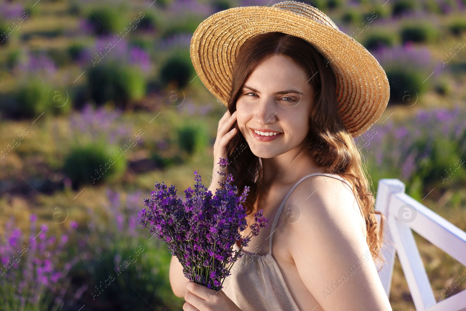 Beautiful young woman with lavender flowers in field Photo of Beautiful young woman with lavender flowers in field
