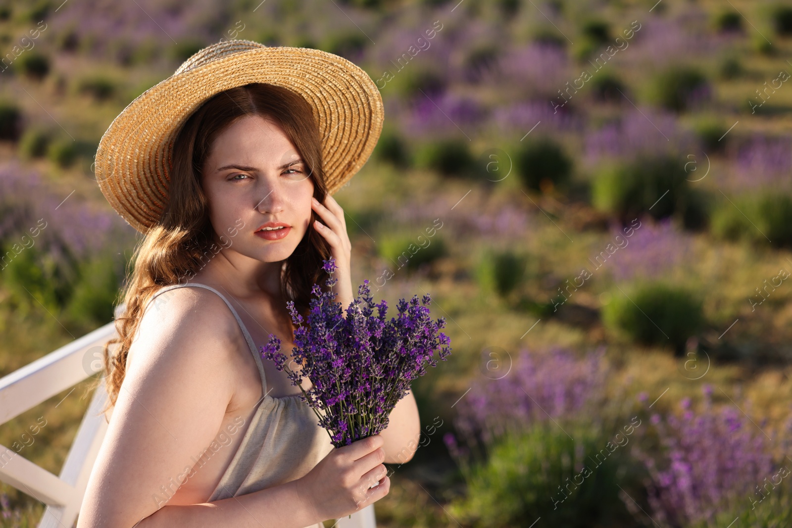 Beautiful young woman with lavender flowers in field. Space for text Photo of Beautiful young woman with lavender flowers in field. Space for text