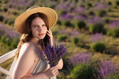 Photo of Beautiful young woman with lavender flowers in field. Space for text