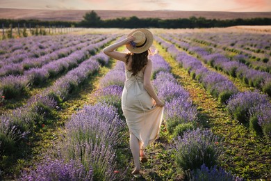 Photo of Woman with straw hat and beautiful flowers running through lavender field