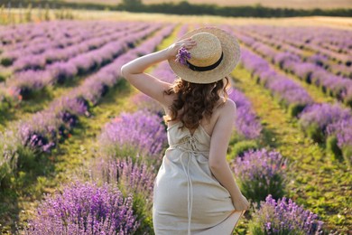 Photo of Woman with straw hat and beautiful flowers running through lavender field
