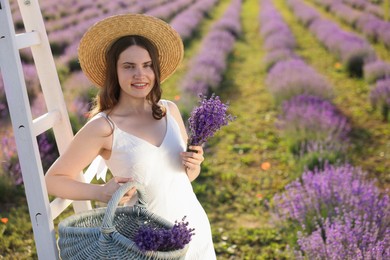 Photo of Beautiful young woman with lavender flowers and wicker basket in field