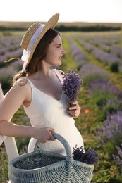 Photo of Beautiful young woman with lavender flowers and wicker basket in field