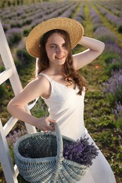 Photo of Beautiful young woman with lavender flowers and wicker basket in field