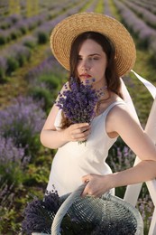Photo of Beautiful young woman with lavender flowers and wicker basket in field