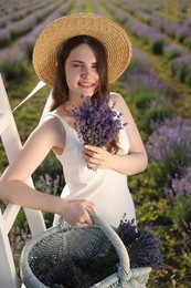 Photo of Beautiful young woman with lavender flowers and wicker basket in field